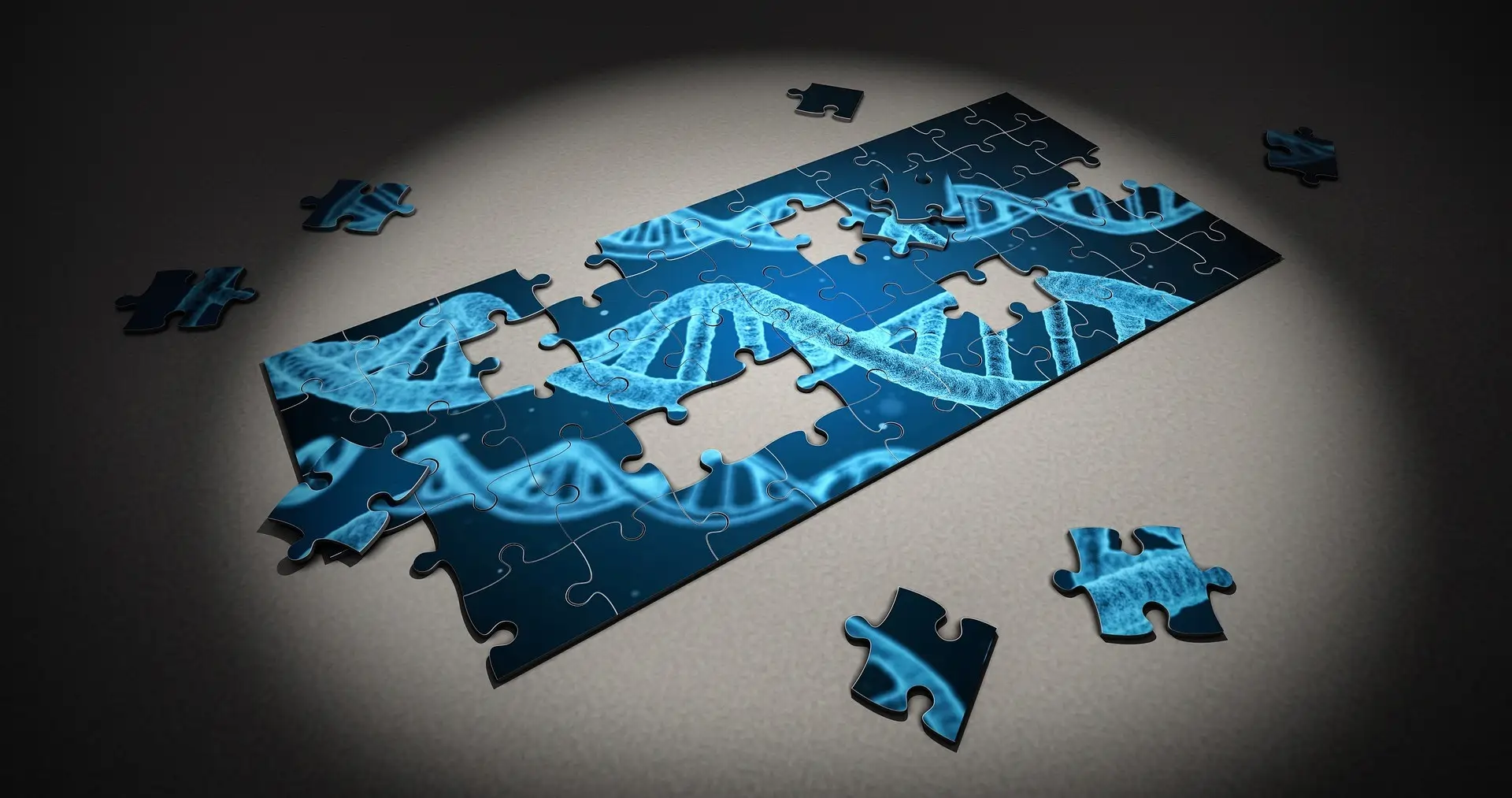 Ein unvollständiges Puzzle zeigt ein DNA-Muster in blauen Tönen, einige Teile liegen verstreut auf einem grauen Untergrund.